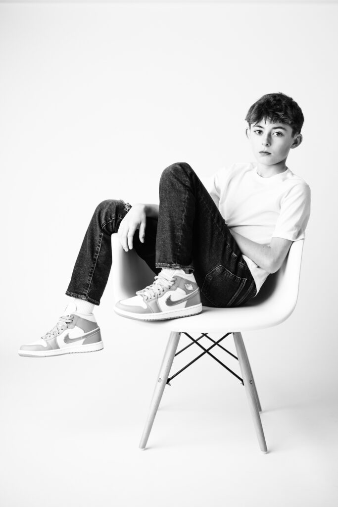 boy posed sitting in chair black and white
