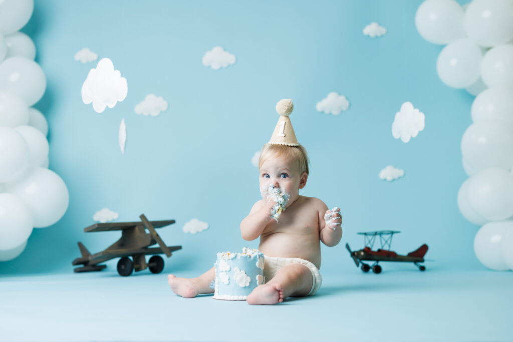 boy eating cake in front of airplane and cloud backdrop