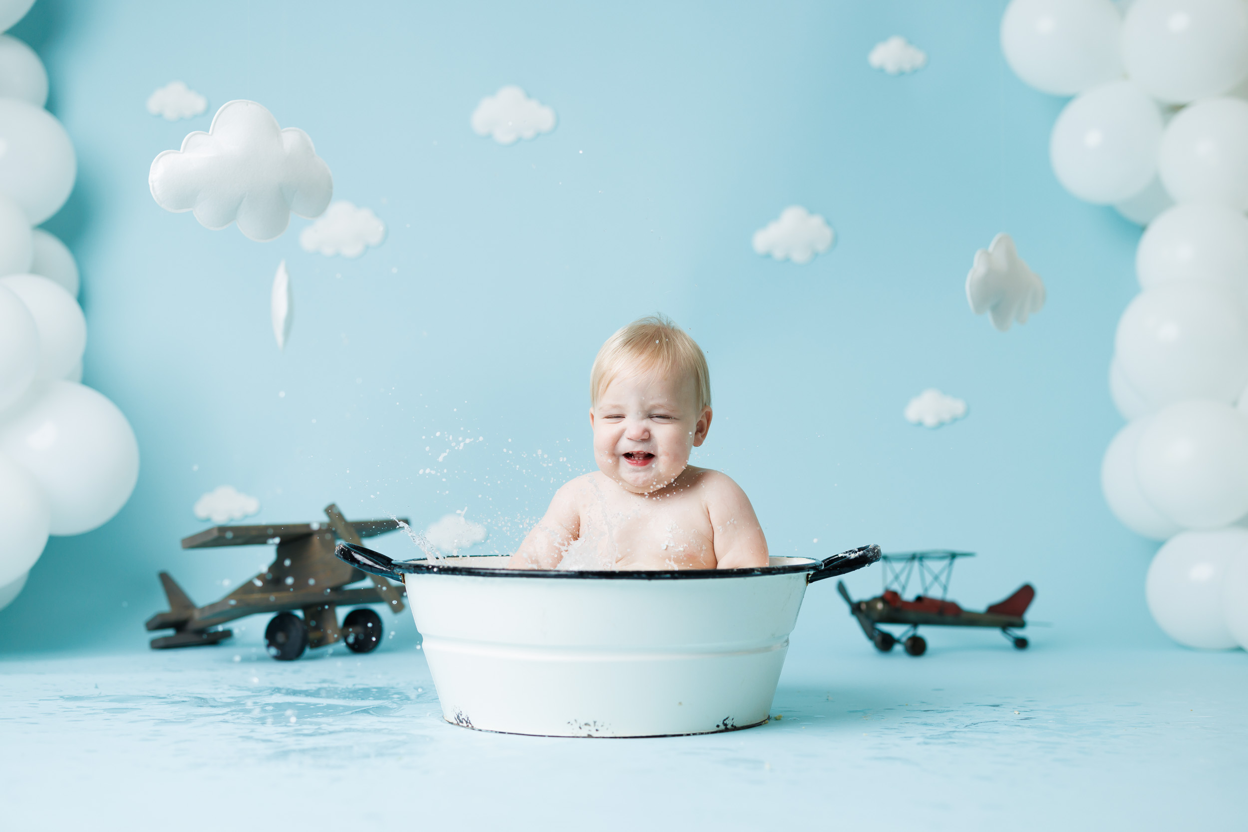 baby in bathtub in front of vintage airplane backdrop