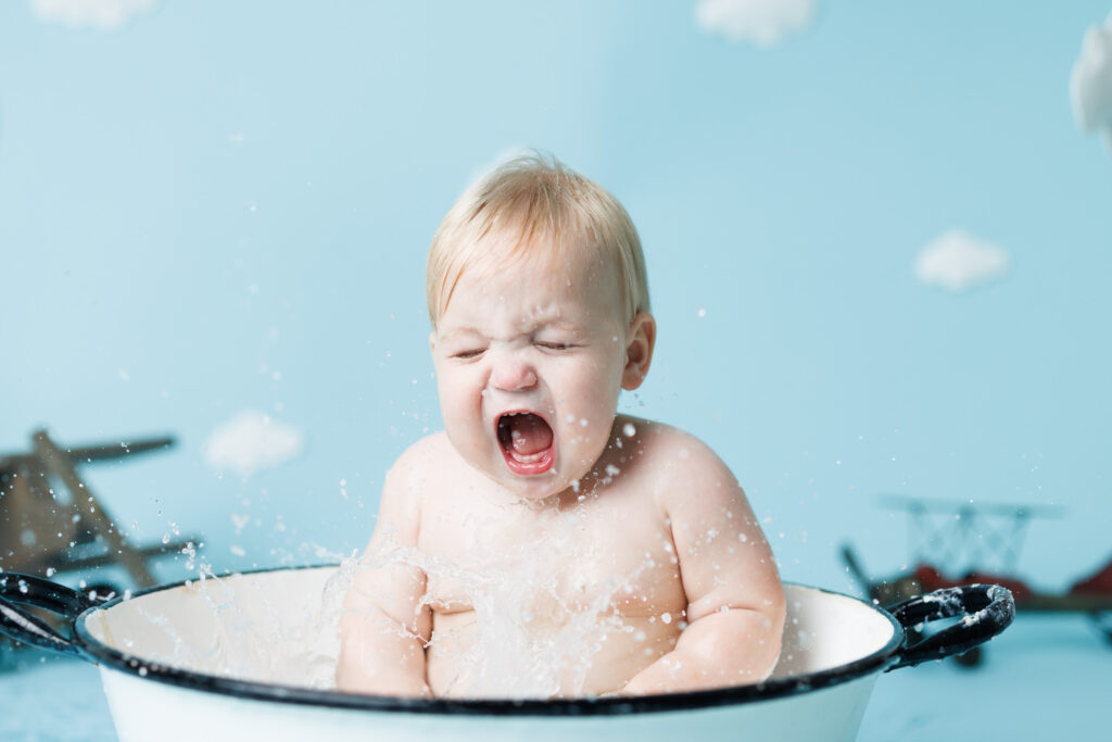 water flying from baby splashing in bathtub 