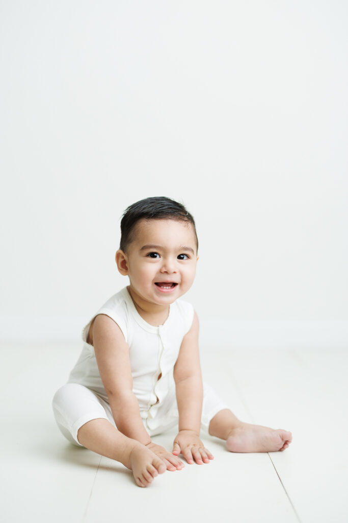 traditional pictures first birthday boy in white romper on white background