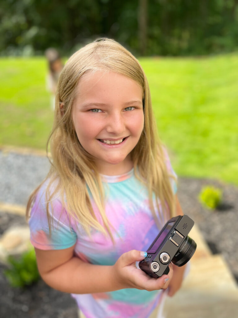 girl smiling holding camera