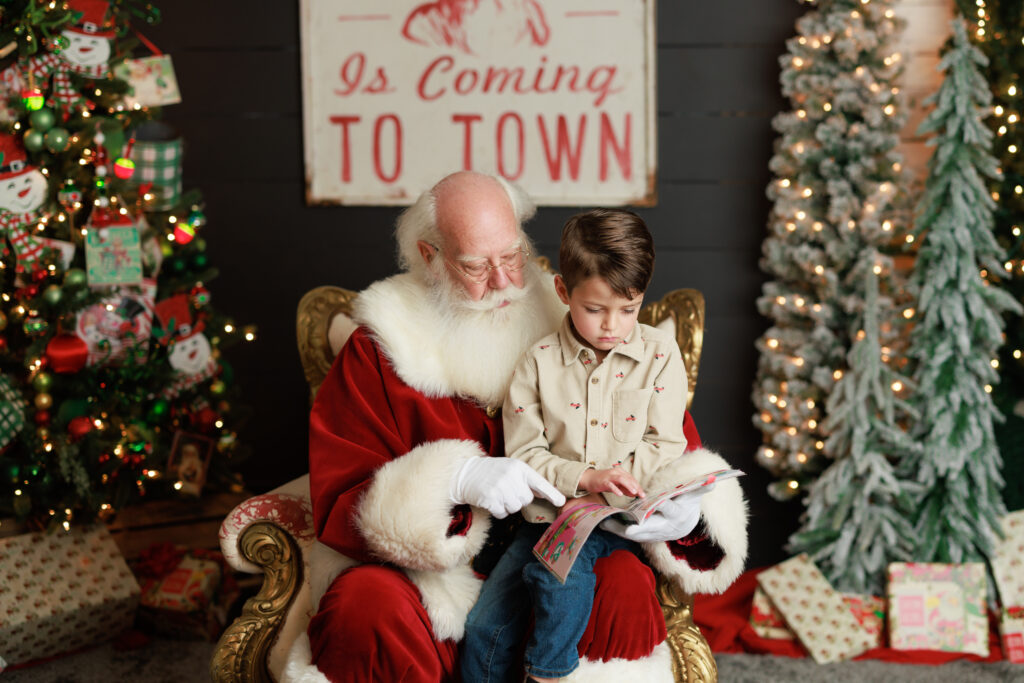 child sitting on santas lap looking through toy magazine 