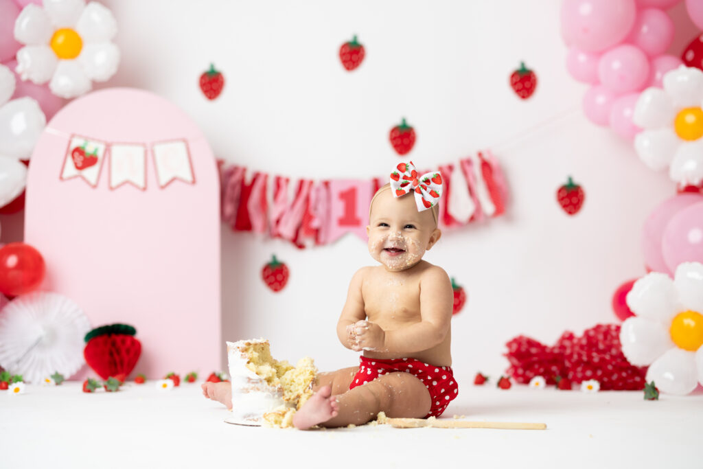 girl smiling pink balloons strawberry daisy first birthday