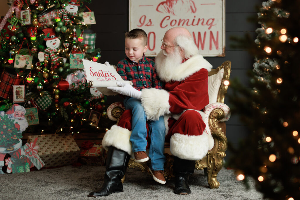 child on santas lap looking for name on the nice list christmas tree lights