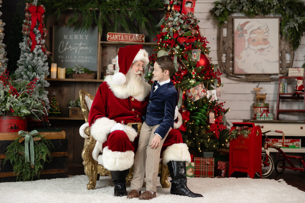 boy in blue velvet jacket looking at santa 