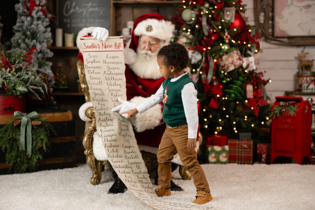 boy in green sweater sees his name on the nice list at santa session