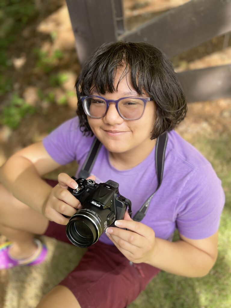 girl in purple holding dslr camera at photography summer camp 