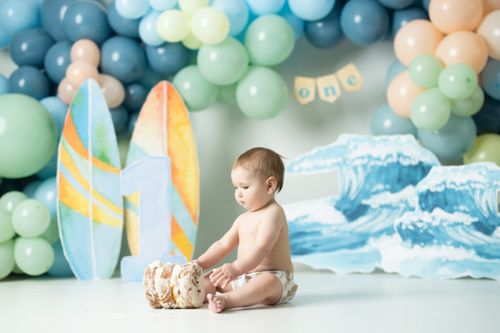 little boy playing in a cake for his surfer themed cake smash session 