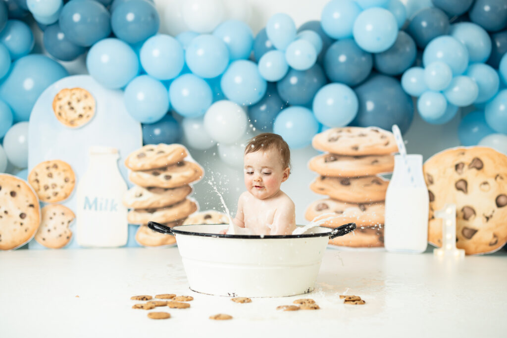 baby splashing in a milk bath at first birthday pictures cookies and milk