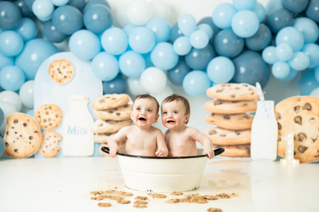 twins enjoying a milk bath that was cookies and milk themed at their first birthday cake smash photography session 