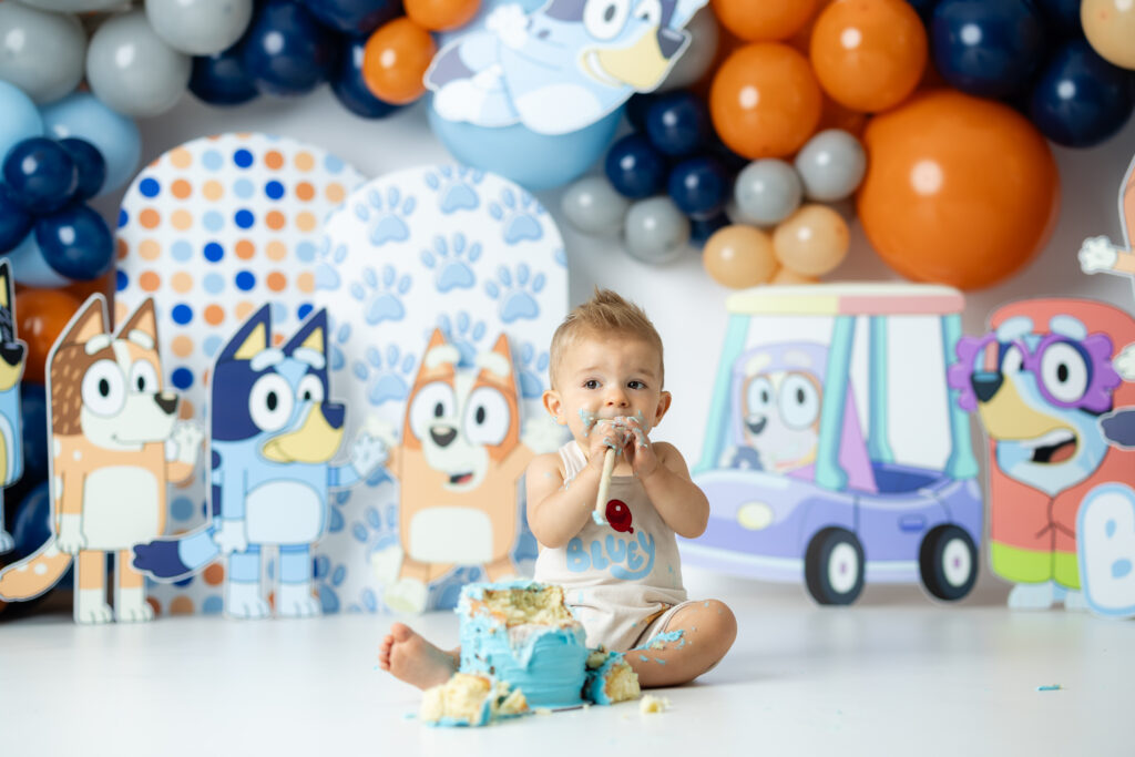 Candid photo of baby with cake-covered hands and joyful expression during cake smash