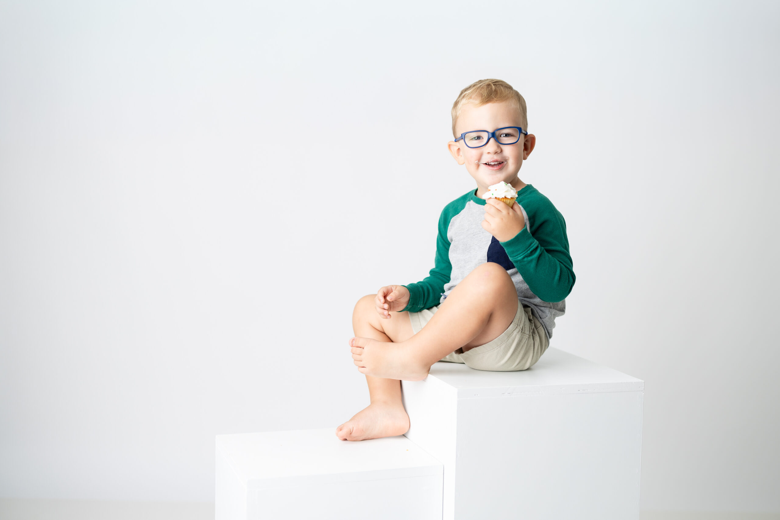 Almost three-year-old enjoying cupcake at studio birthday session