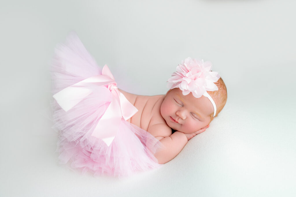 Newborn redhead baby girl in soft pink floral headband and adorable pink tutu
