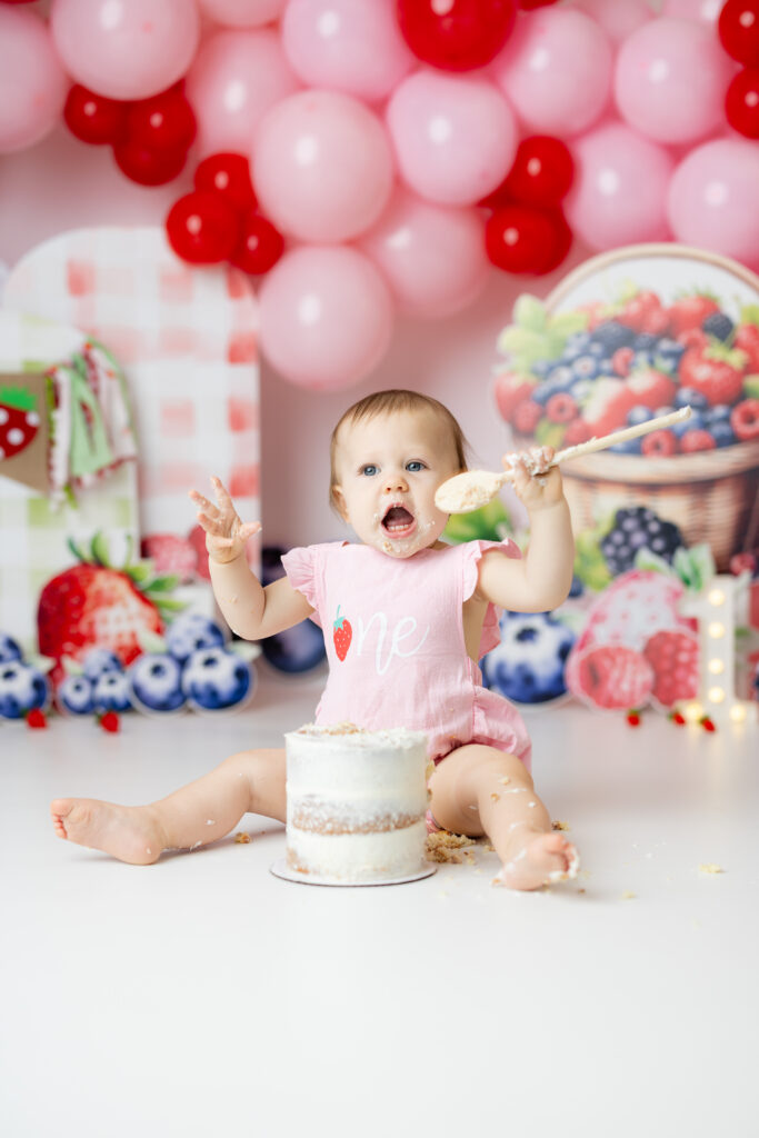 One year old gently eating cake during berry first birthday session in Canton GA
