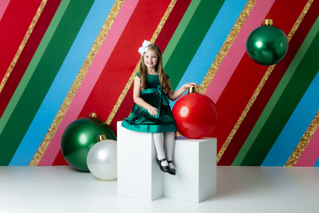 Child smiling in front of colorful Christmas tree set – Colorful Christmas Sessions Canton GA