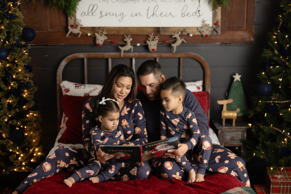 Family wearing Christmas pajamas during pajama mini session on real bed set