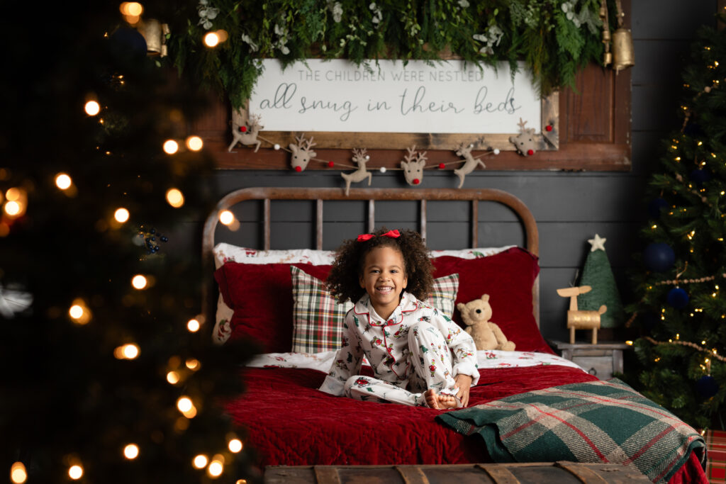 Child jumping on custom Christmas pajama mini session bed in Canton GA studio