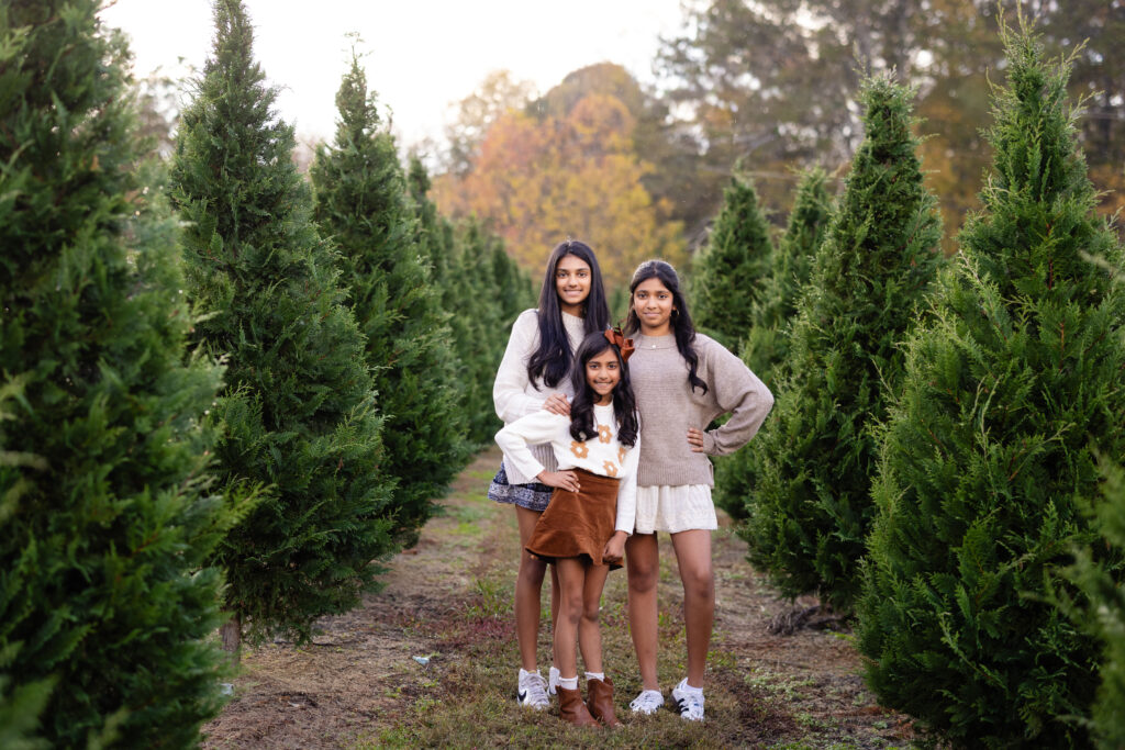 Sisters smiling together in Christmas tree farm session.