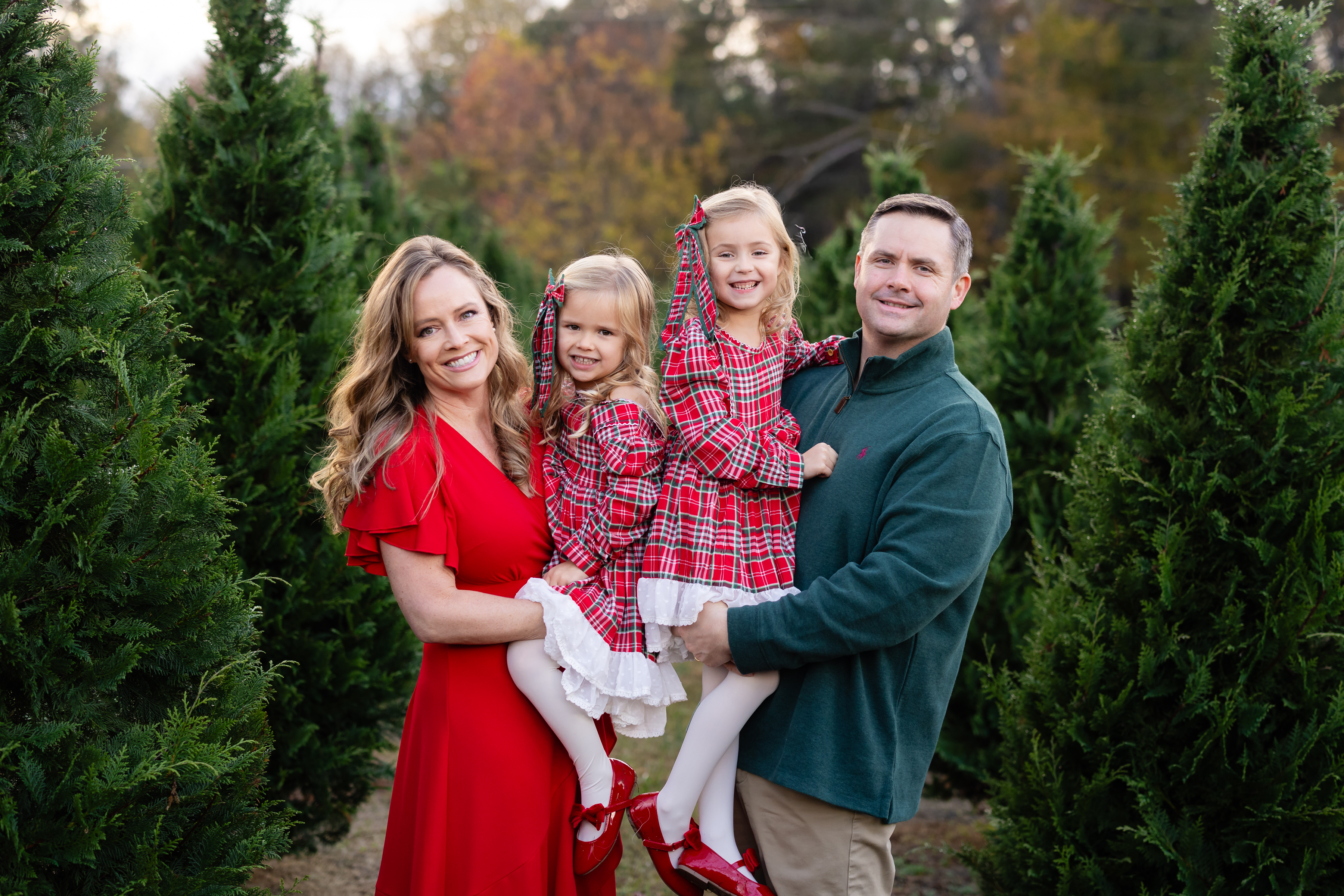 Family in red plaid dresses during Christmas tree farm photos.