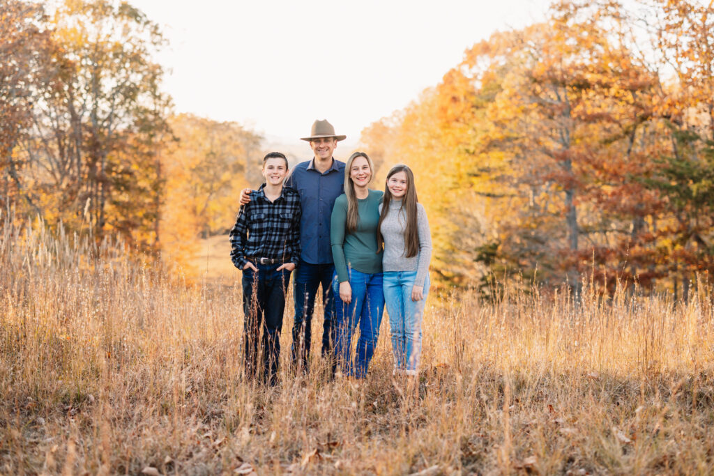 Family walking hand-in-hand through field at sunset.