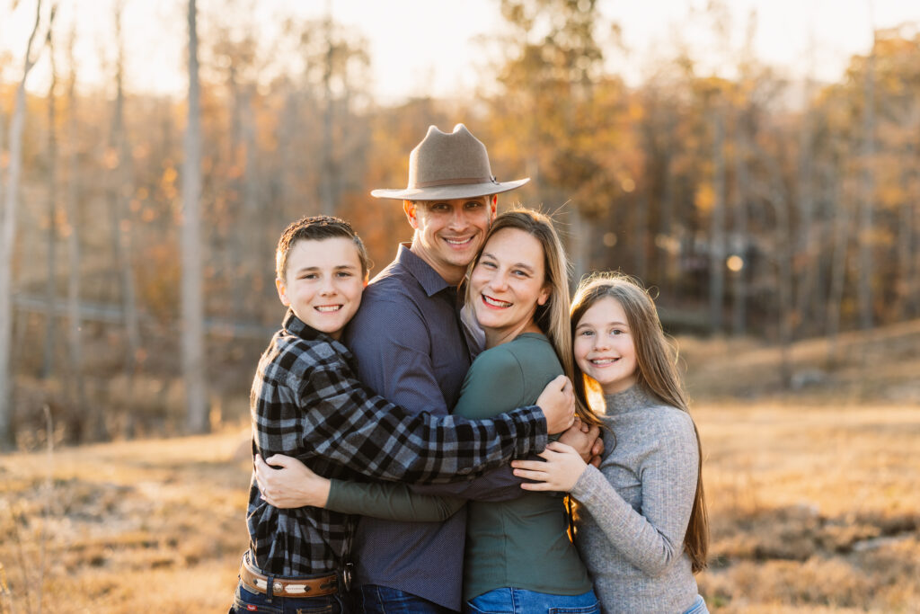 Family standing in a grassy field at sunset during fall photo session