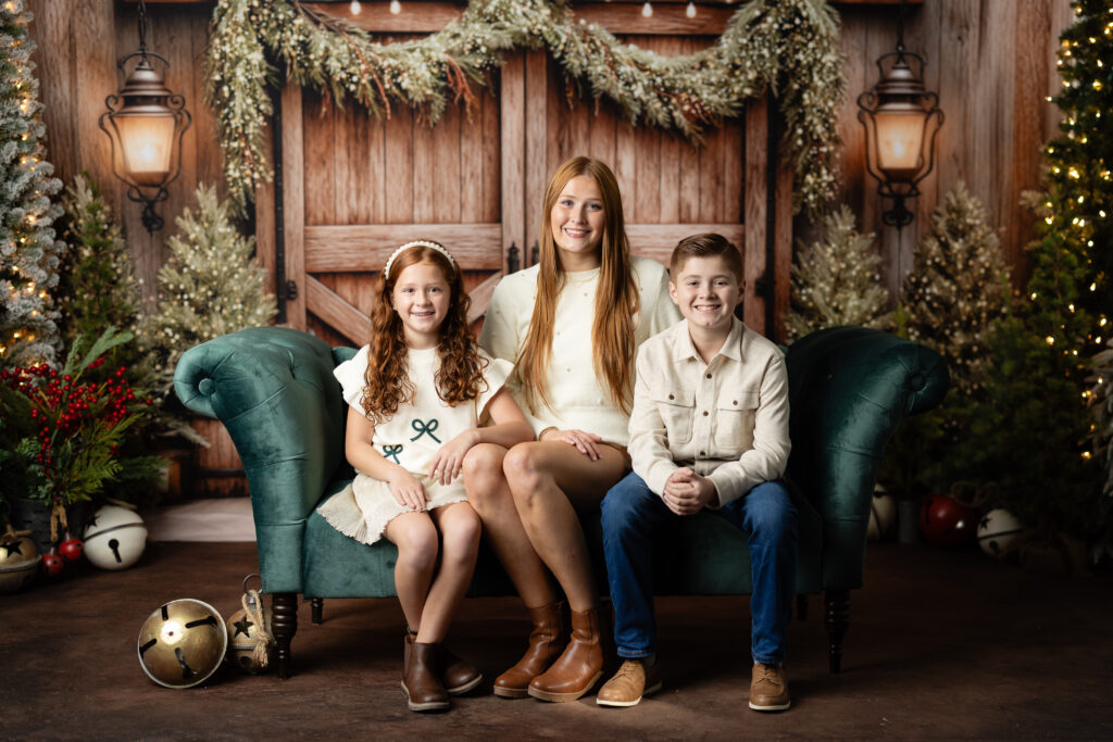 Siblings sitting together on Aspen studio Christmas set in Canton GA