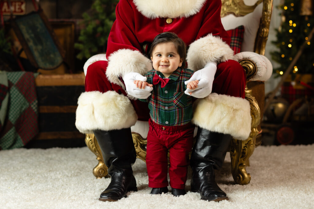 Baby standing with Santa during A Date with Santa 2026 Canton GA session in a festive studio setup.