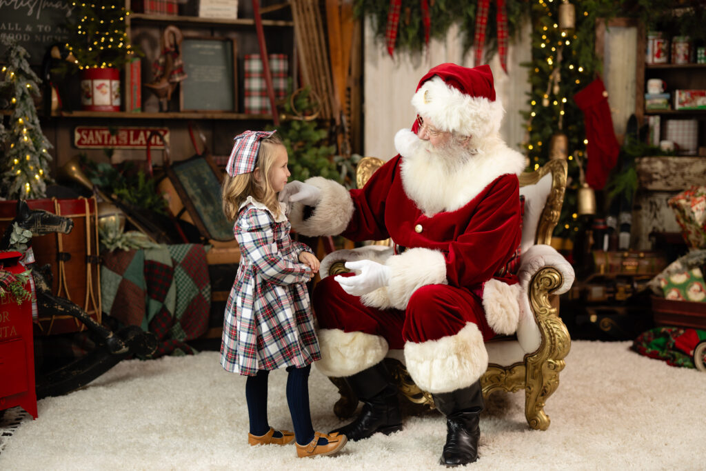 Little girl meeting Santa during A Date with Santa 2026 Canton GA session in a warm, rustic Christmas set.