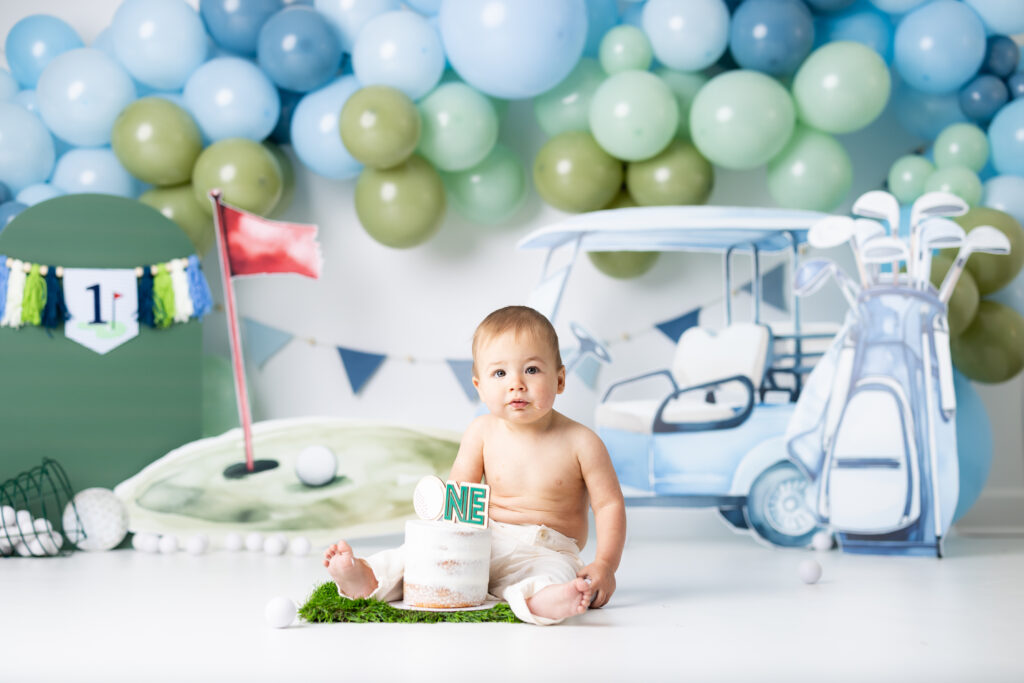 Golf themed cake smash setup with golf cart and putting green