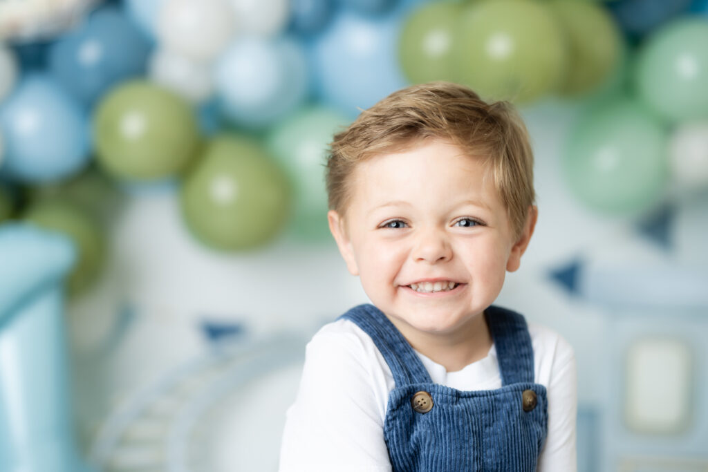 boy smiling during train themed birthday photoshoot
