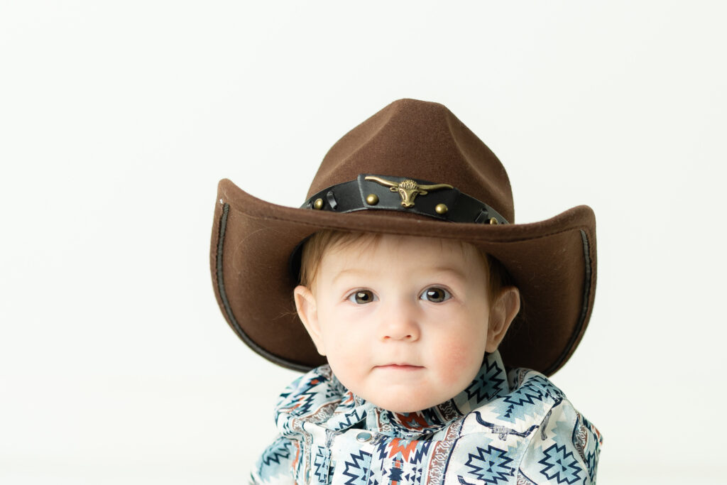 One year old wearing cowboy hat during cake smash photography session
