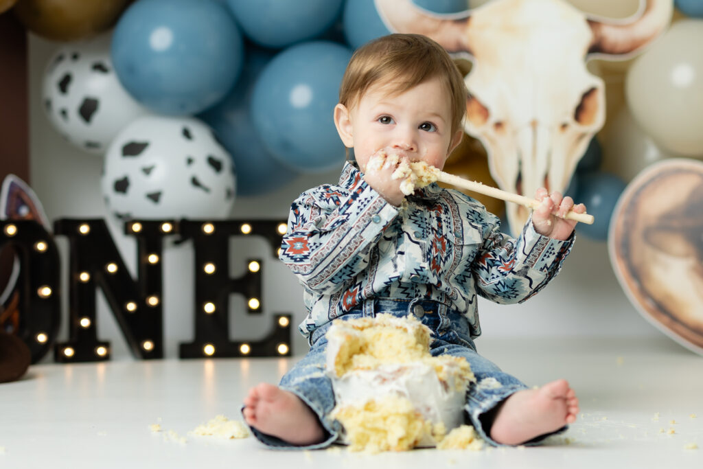 Baby boy enjoying cowboy cake smash first birthday session in North Georgia