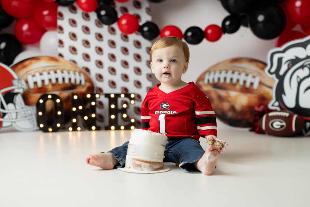 One-year-old boy smashing his birthday cake on a Georgia football set