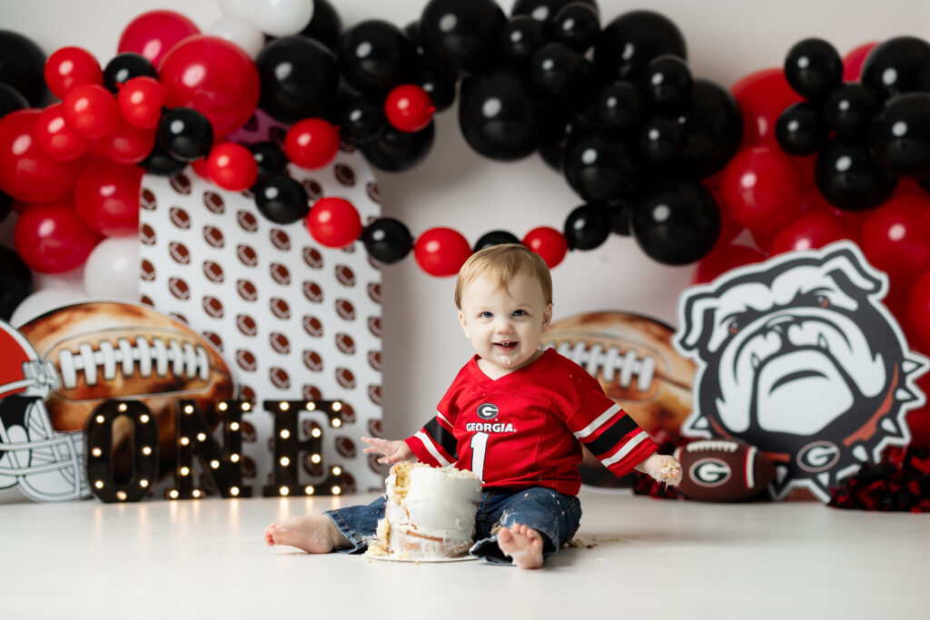 One-year-old boy smashing his birthday cake on a Georgia football set